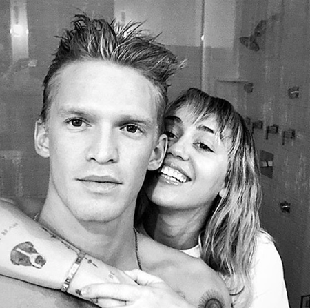 Cody Simpson and Miley Cyrus taking pictures in the bathroom.